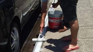 Homem pinta o meio-fio de branco para estacionar carro em Capão da Canoa